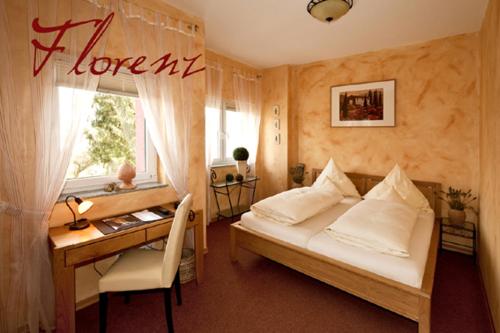 a bedroom with a bed and a desk and a window at Hotel & Restaurant 4 Winden in Windhagen