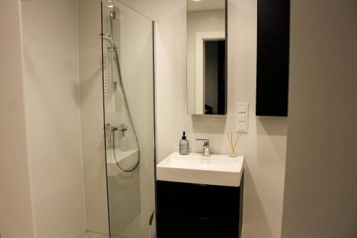 La salle de bains blanche est pourvue d'un lavabo et d'une douche. dans l'établissement O! Shellter Apartment PREMIUM by Oskar, à Rogowo
