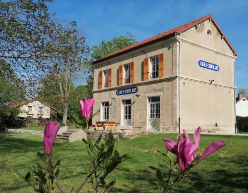 an old building with pink flowers in front of it at La Gare de Lurey Conflans gîte et hébergements insolites en Champagne in Esclavolles-Lurey