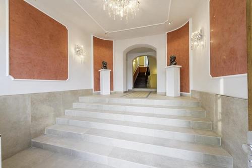 a hallway with stairs in a building with a chandelier at Palace am See in Tegernsee
