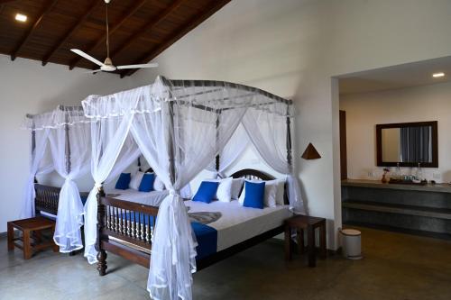 1 dormitorio con cama con dosel y almohadas azules en Beach Inns Holiday Resort - Celeste, en Matara