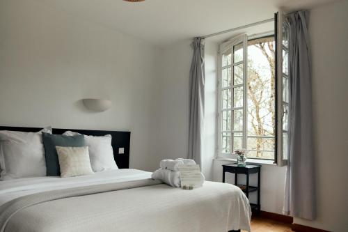 a bedroom with a large white bed with a window at La Maison du Gasseau in Saint-Léonard-des-Bois