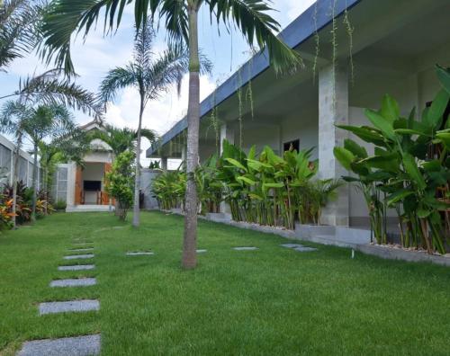 a courtyard of a house with palm trees and grass at kamala in Selong Belanak