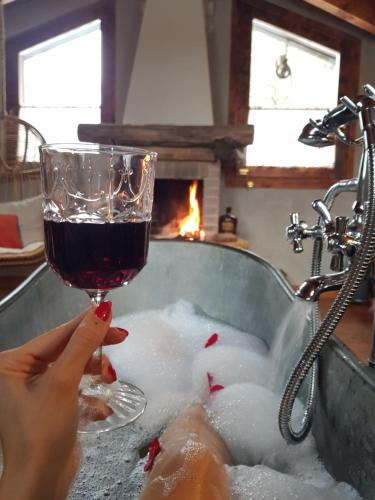 a woman is holding a glass of wine in a bath tub at La Bottega del Drago in Santa Brigida