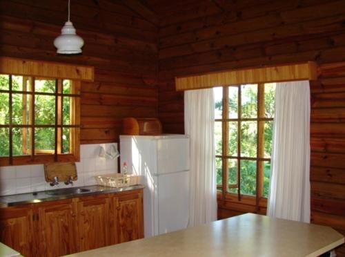 a kitchen with a white refrigerator and two windows at Lisbon Eco Lodge in Graskop