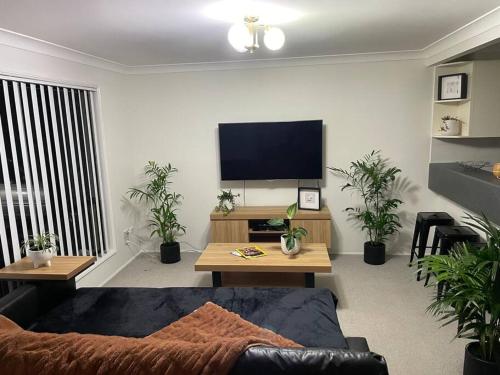 a living room with a couch and a flat screen tv at Our Townhouse in Toowoomba in Toowoomba
