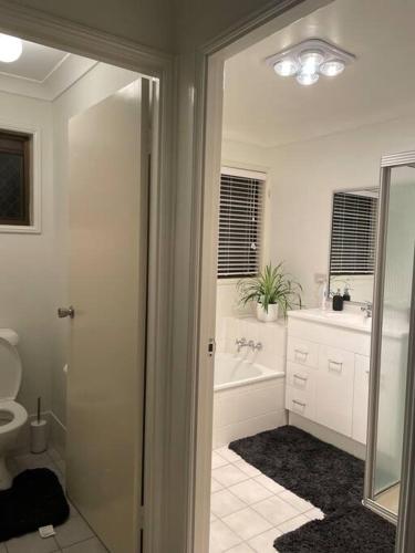 a bathroom with a tub and a sink and a toilet at Our Townhouse in Toowoomba in Toowoomba