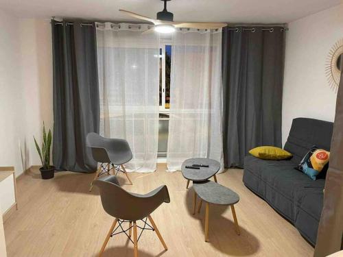 een woonkamer met een bank en stoelen voor een raam bij Cocooning en rez de jardin in Saint-Pierre