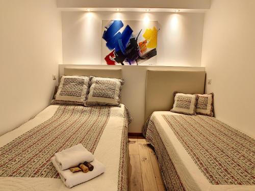 duas camas num quarto com um quadro na parede em Grand studio cabine à côté des plages NER634 em Cannes
