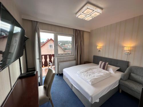 Hotel Austria في غابلتز: غرفه فندقيه بسرير وكرسي وتلفزيون