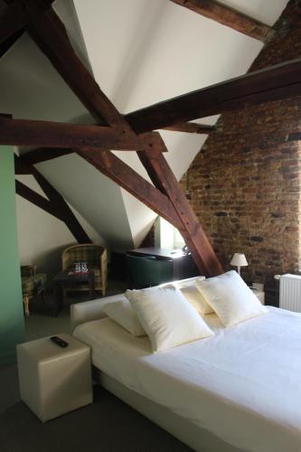 a bedroom with a large white bed with wooden beams at Amaryllis Hotel Veurne in Veurne