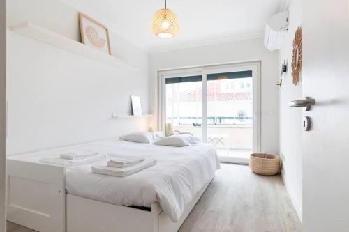 a white bedroom with a white bed and a window at Cascais Center 3 bdr - Family Haven in Cascais