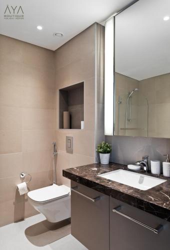 a bathroom with a sink and a toilet and a mirror at Fancy One Bedroom Apartment in Downtown Dubai By ĀYA Boutique in Dubai