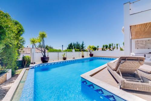 una piscina con una sedia accanto a una casa di Ocean View Villa a Boliqueime