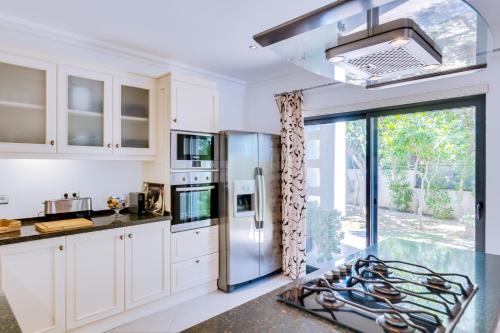 una cucina con armadi bianchi e frigorifero in acciaio inossidabile di Ocean View Villa a Boliqueime