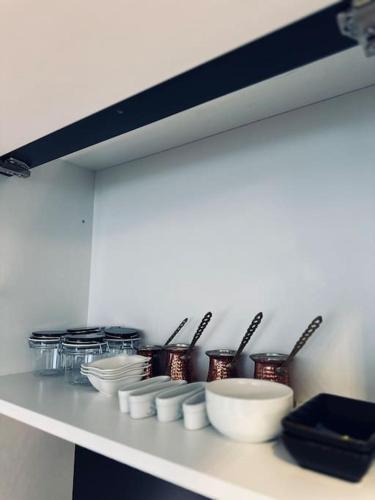 a shelf with bowls and utensils in a kitchen at Priam Apartment in Pristina