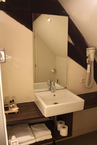 a bathroom with a white sink and a mirror at Amaryllis Hotel Veurne in Veurne