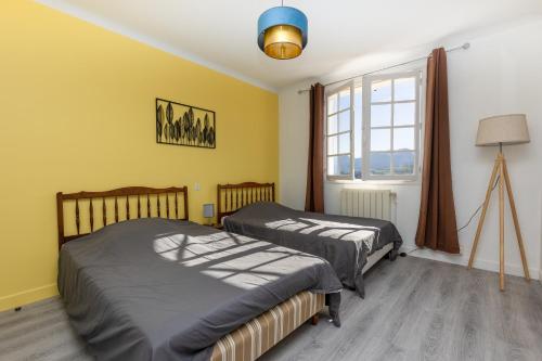 Duas camas num quarto com paredes amarelas e uma janela em Maison Pikassariko - 4 Chambres proche frontière espagnole em Sare