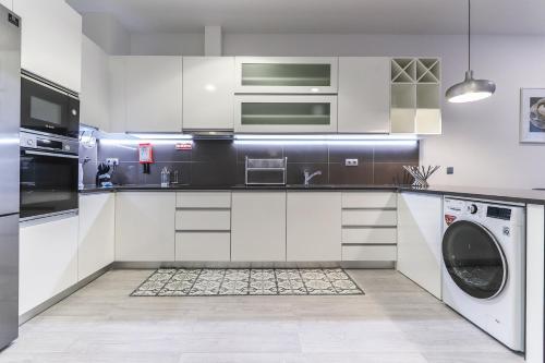 a kitchen with white cabinets and a washer and dryer at Vita Portucale ! Moscavide Family Apartment in Lisbon