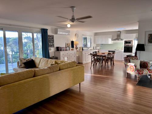 a large living room with a couch and a kitchen at Magic Beach Cottage in Venus Bay