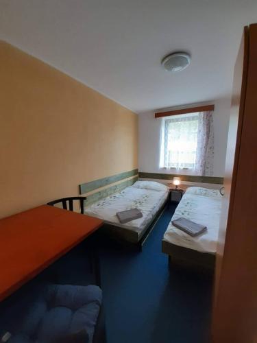a room with two beds and a table and a window at Nad rybníkem Hnačov - rodinný rekreační areál in Hnačov