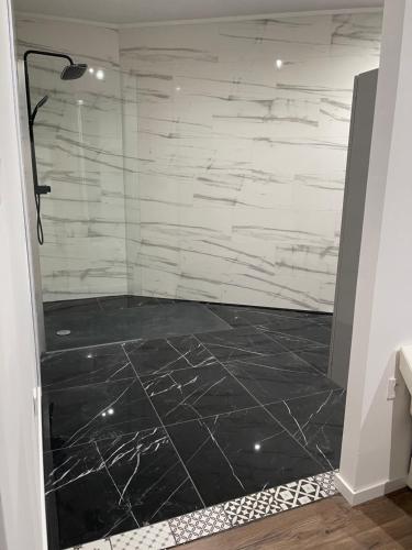 a bathroom with a shower with black and white marble at Cocoon’in in Raismes