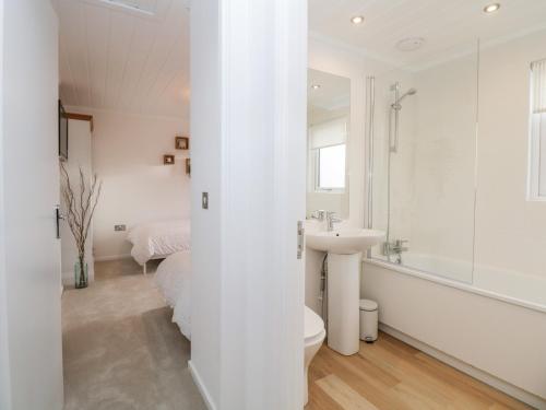 a white bathroom with a sink and a toilet at Hollytree Lodge in Windermere