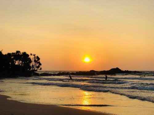 two people walking on the beach at sunset at Sahana Sri Villa in Bentota