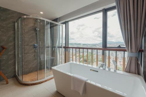 ein Badezimmer mit einer Badewanne und einem Balkon in der Unterkunft White Swan Guest House MeiZhou in Meizhou