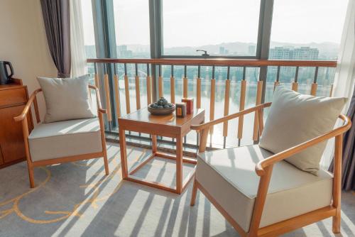 a room with two chairs and a table and a balcony at White Swan Guest House MeiZhou in Meizhou