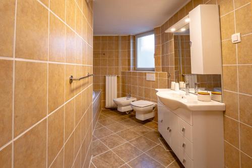 a bathroom with two sinks and a toilet and a window at Alpski škrat, Kranjska Gora in Kranjska Gora