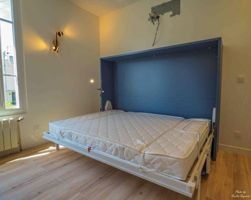 a large bed in a room with a blue headboard at Studio de Luxe Meublé ,Clim et Parking Options, lave-linge in Bagneux