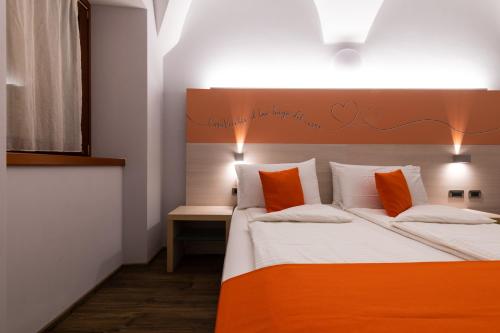 a bedroom with a bed with orange and white pillows at Albergo Casavecchia in Tiarno di Sopra