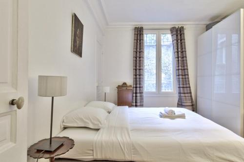biała sypialnia z dużym białym łóżkiem i oknem w obiekcie Appartement Caulain - Welkeys w Paryżu
