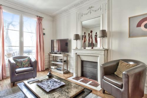 uma sala de estar com duas cadeiras e uma lareira em Exceptional flat at the heart of Montmartre - Paris - Welkeys em Paris