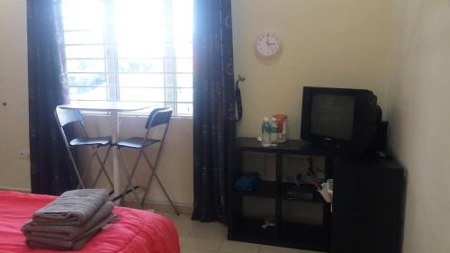 a bedroom with a bed and a table and a tv at GLG KLIA Transit House in Sepang