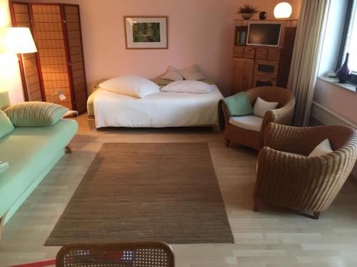 a bedroom with a bed and two chairs and a couch at Guest Apartment Unterbach in Düsseldorf