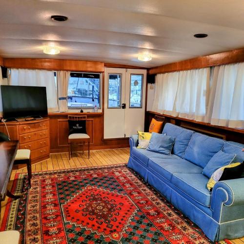 a living room with a blue couch and a tv at Don Maximo Yacht Hotel in Vigo