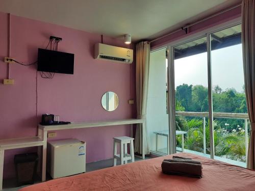 Un dormitorio con una pared de color rosa con una cama y una ventana en Pingplalee Resort, en Sai Yok