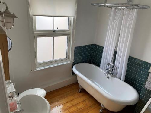 a bathroom with a tub and a toilet and a sink at Demeter Cottage in Whitby