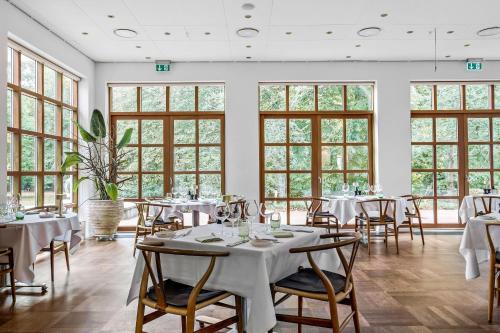 een eetkamer met tafels, stoelen en ramen bij Gl Skovridergaard in Silkeborg