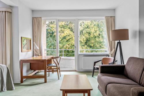 a living room with a couch and a desk and a window at Gl Skovridergaard in Silkeborg