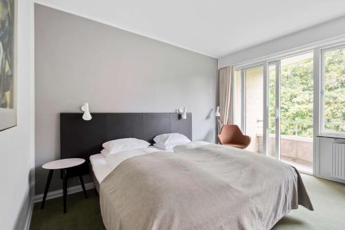 a white bedroom with a large bed and a chair at Gl Skovridergaard in Silkeborg