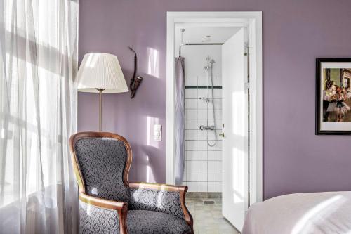 a bedroom with a chair and a shower at Gl Skovridergaard in Silkeborg