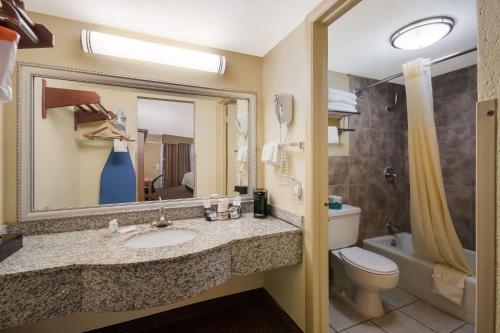 La salle de bains est pourvue d'un lavabo, de toilettes et d'un miroir. dans l'établissement Quality Inn, à Chickasha