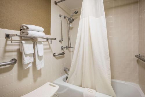 a bathroom with a white shower curtain and a toilet at Quality Inn and Suites Fairgrounds - Syracuse in Liverpool