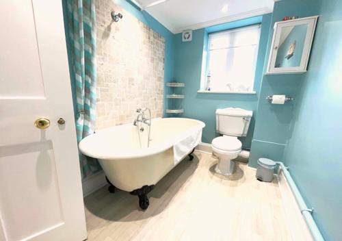 a bathroom with a white tub and a toilet at The Georgian Apartment in Gosport