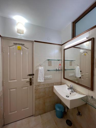 een badkamer met een wastafel, een spiegel en een douche bij Villa Bliss Lake View in Nainital