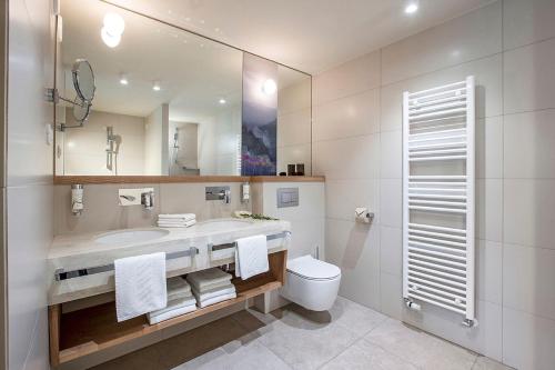 a bathroom with a sink and a toilet and a mirror at Hotel Park - Sava Hotels & Resorts in Bled