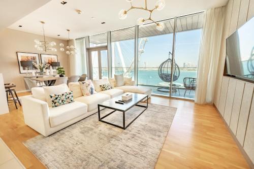 een woonkamer met een witte bank en een tafel bij FAM Living Bluewaters - Island Living - Ain Dubai & Sea View in Dubai